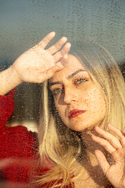 istock Sad young woman looking through window on rainy day 1316849899