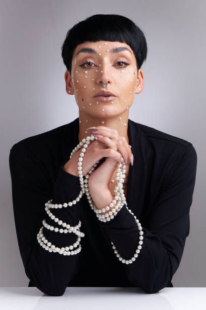 Studio portrait of a beautiful young woman with pearls on her face posing against a grey background A woman needs ropes and ropes of pearls septum piercing stock pictures, royalty-free photos & images