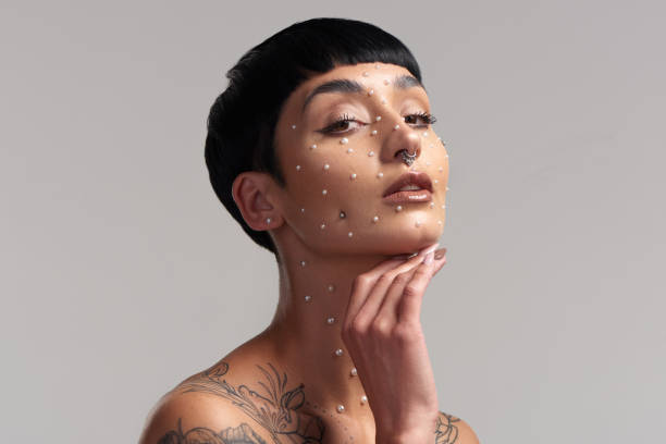 retrato de estudio de una hermosa joven con perlas en la cara posando sobre un fondo gris - bizarre women portrait pierced fotografías e imágenes de stock