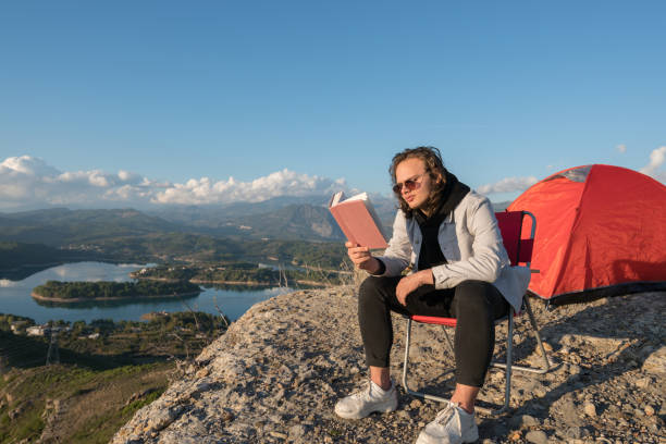 istock Young traveler reading book on the mountain peak 1316858133