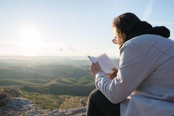 istock Young traveler reading book on the mountain peak 1316858173