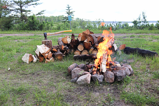 A large campfire with chopped wood behind it.