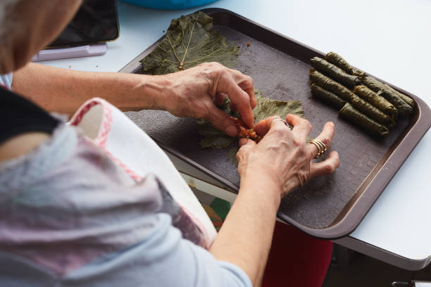 a woman preparing wraps made from grape leaves - dolmades imagens e fotografias de stock