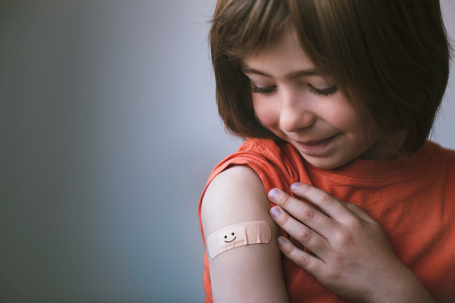 Retrato de un niño sonriente con vendaje adhesivo en la mano después de la vacunación photo