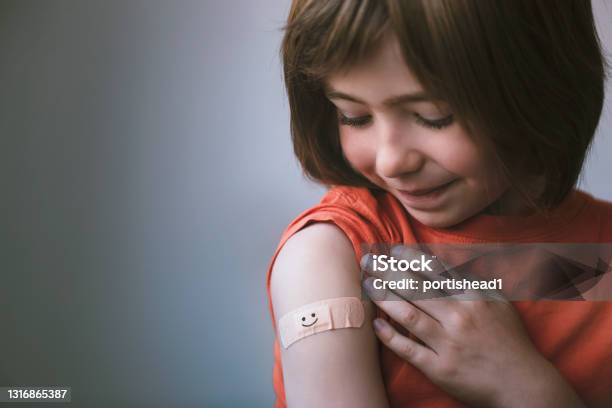 Portrait Of Smiling Little Child With Adhesive Bandage On His Hand After Vaccination Stock Photo - Download Image Now