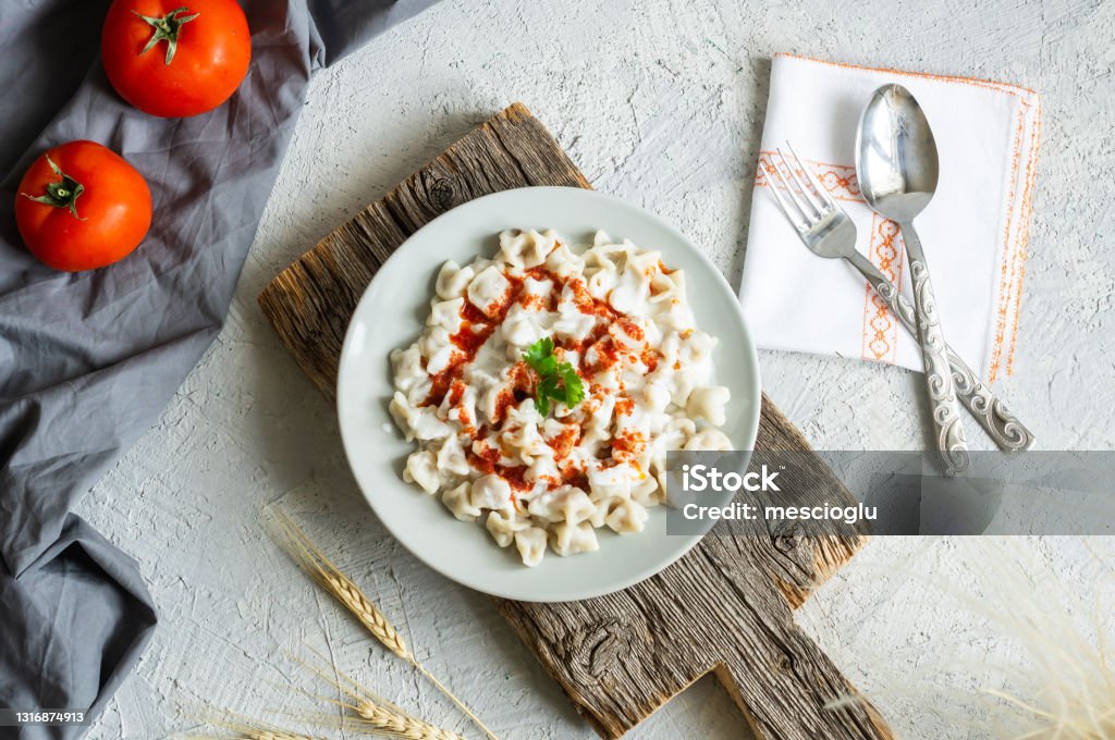 Turkish traditional food ravioli with yoghurt and tomato sauce in plate, manti Dumpling Stock Photo