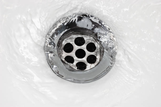istock Sink plug drain hole bath plughole, white basin spout, running water macro closeup, stainless steel, china porcelain hand washbasin, large detailed bright horizontal wash-hand swirl flat lay detail, environment saving bathroom concept 1316875141