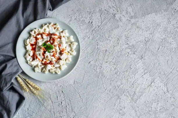 Photo of Turkish traditional food ravioli with yoghurt and tomato sauce in plate, manti