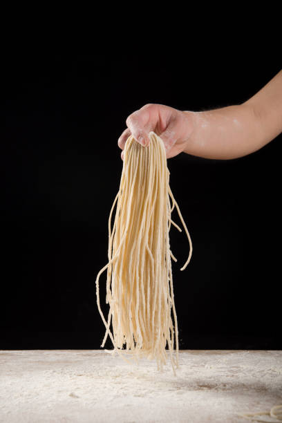 istock Hand holding noodle Studio shot on black background 1316876014