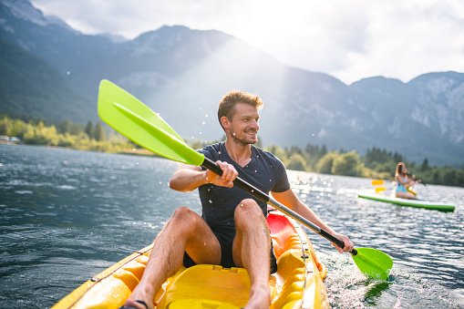 Front view of mid adult Caucasian male kayaker smiling and looking away from camera as he enjoys paddling on vacation in Triglav National Park, Slovenia.