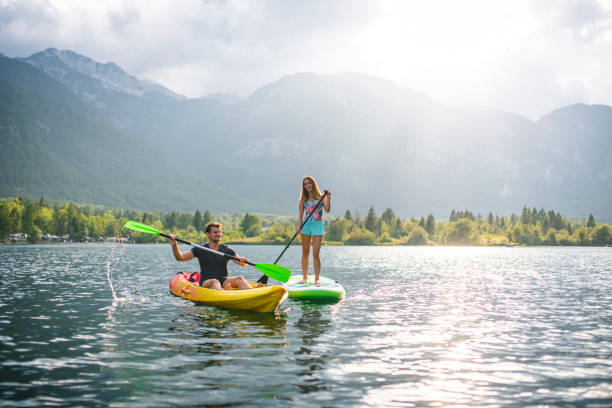 paddleboarder and flatwater kayaker exploring lake bohinj - lake bohinj imagens e fotografias de stock