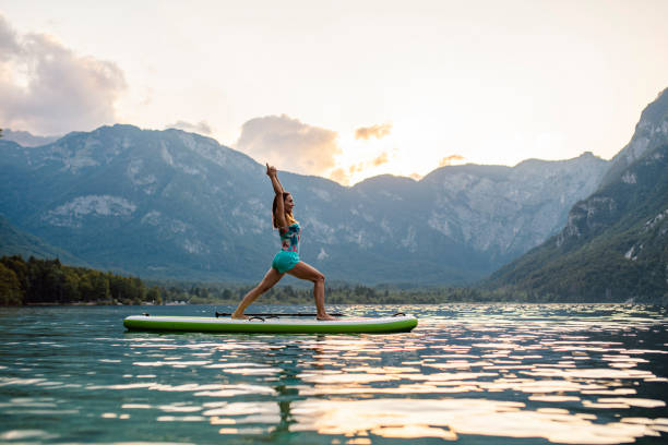 istock Tranquil Scene of Woman Doing Warrior I Pose on Paddleboard 1316878145