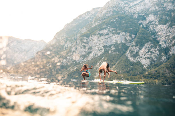 wakacje para skacząc off paddleboard do jeziora bohinj - alp descent zdjęcia i obrazy z banku zdjęć