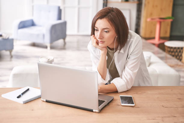 Young woman sitting at home. Working on notebook