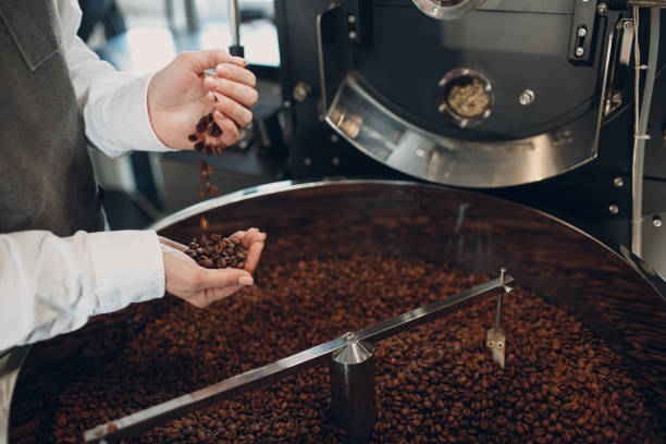 istock Coffee cooling in roaster machine at coffee roasting process. Young woman worker barista Mixing coffee beans. 1316878242