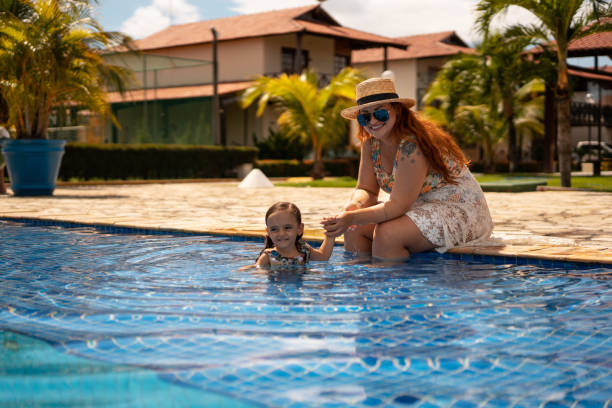 madre e figlia in piscina - women wading sun hat summer foto e immagini stock