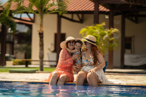 famiglia che si diverte nella piscina condominiale - women wading sun hat summer foto e immagini stock