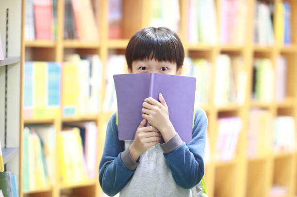 istock Happy Asian kid reading book in library 1316885828