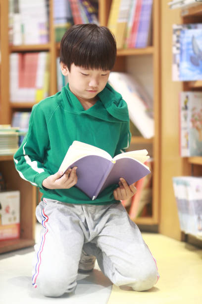istock Happy Asian kid reading book in library 1316885838
