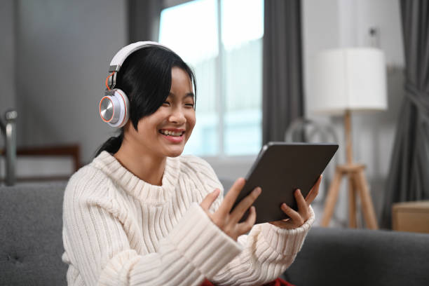istock Cheerful young woman wearing headphone and using digital tablet at home. 1316899467