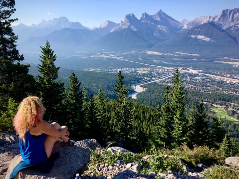 Woman overlooking view of Three Sisters Mountain from the Lady MacDonald hiking trail in Canmore, Alberta, Canada.
