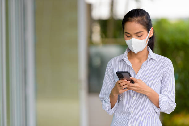 istock Woman wearing face mask to protect from coronavirus Covid-19 while using phone 1316900063