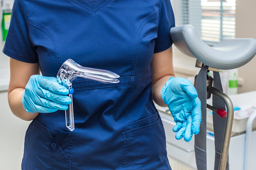 Ginecólogo sosteniendo un espéculo ginecológico con guantes photo