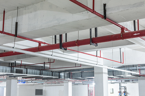 Fire protection sprinkler system with red pipes is placed to hanging from the ceiling