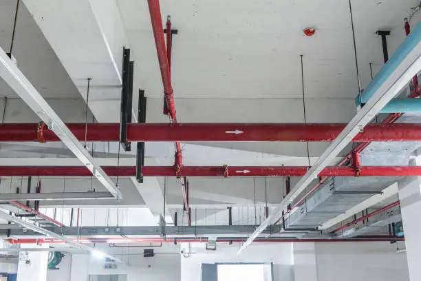 Fire protection sprinkler system with red pipes is placed to hanging from the ceiling