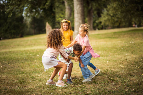 Group of happy children sit on the floor with joined hands and looking at camera