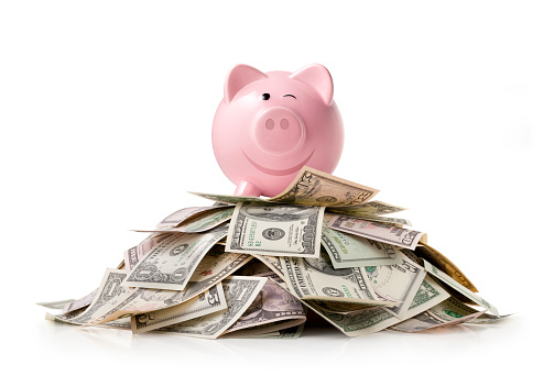 Piggy bank on stack of a pile of money isolated on a white background.