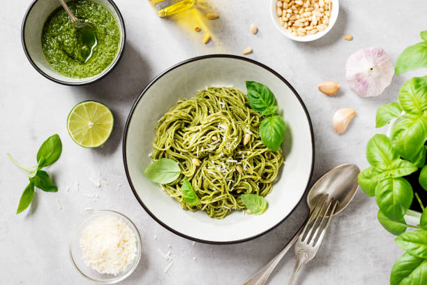 spaghetti di pasta al pesto e foglie di basilico fresco - pasta foto e immagini stock