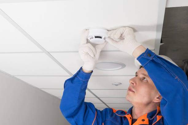 istock a worker installs a smoke and fire detector on the ceiling in the office, close-up 1316913882