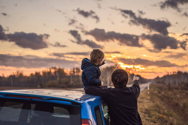 Dad and son are resting on the side of the road on a road trip. Road trip with children concept Dad and son are resting on the side of the road on a road trip. Road trip with children concept. road trip stock pictures, royalty-free photos & images