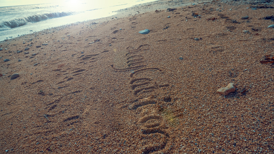 The word Staycation written in sand on a beach in warm summer sunshine.