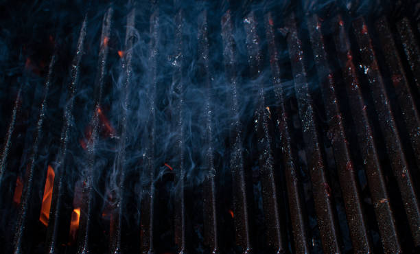 Empty flaming BBQ charcoal grill with smoke.