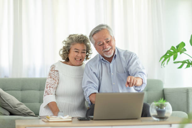 istock Happy Wellness Asian Elderly or Seniors couple with white hairs using computer laptop VDO Conference Call online meeting with family and smile at home,Retirement lifestyle at home concept 1316926441