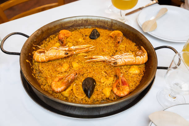 köstliche traditionelle valencianische meeresfrüchte paella (herzhafte sreisgericht mit garnelen, tintenfisch und muscheln) in paella pan - beer food paella clam stock-fotos und bilder