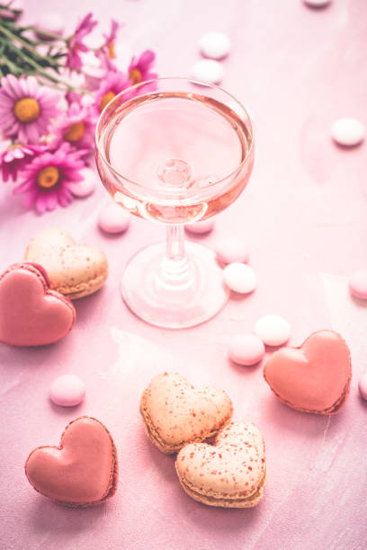 с днем матери - сладкие макароны в форме сердца и бокал розового игристого вина - pink champagne стоковые фото и изображения
