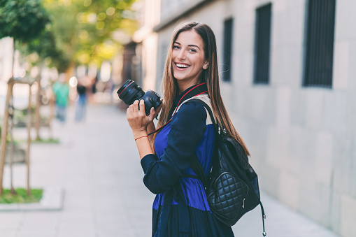 Portrait of smiling woman with camera looking over the shoulder