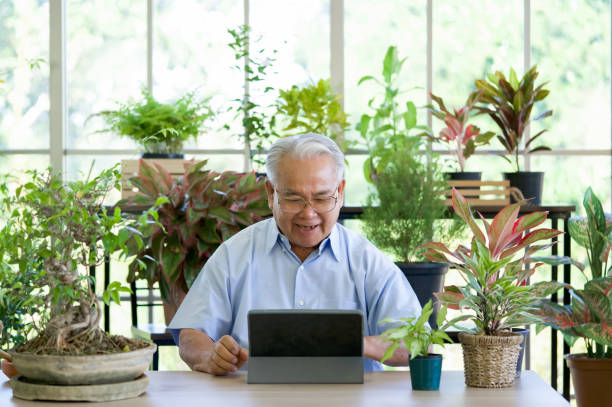 istock A retired old man use wireless communication via a tablet computer to inquire about indoor garden care from botanist. The morning atmosphere in the greenhouse planting room. 1316936469