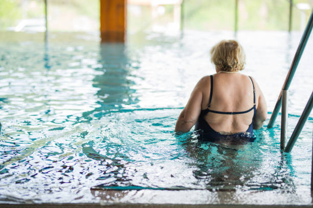スイミングプールに入る年配の女性 - swimming exercising women back ストックフォトと画像