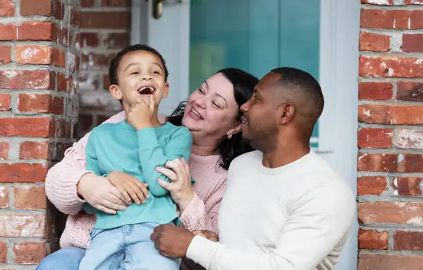 Photo of Interracial family with boy sitting on front stoop