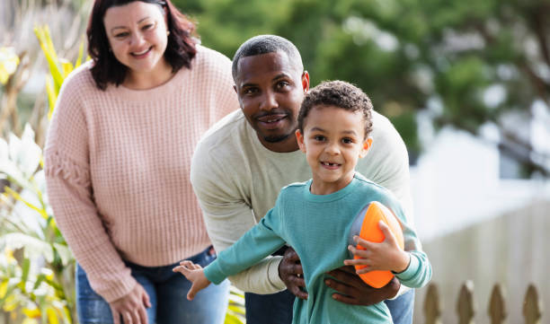 istock Boy, father playing with football in yard, mom watching 1316937405