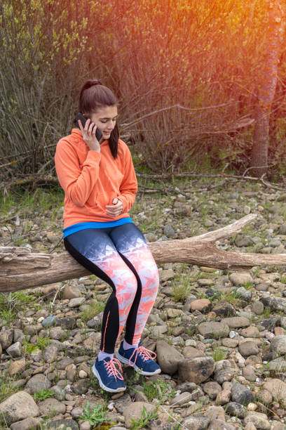 istock young teenager in sportswear resting on a tree branch calling on a cell phone while taking a break from running in the field with selective focus 1316937809