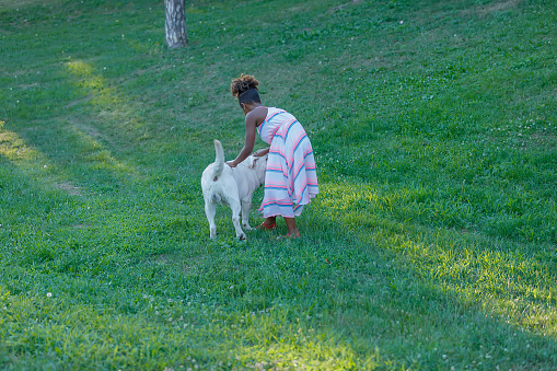 Cute African-American Girl in Dress, With Curly Hair is Enjoying in Summer Day With her Little Dog.