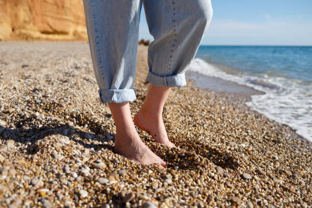 nahaufnahme foto. nackte füße in versteckten jeans auf dem sand - child human foot barefoot jeans stock-fotos und bilder