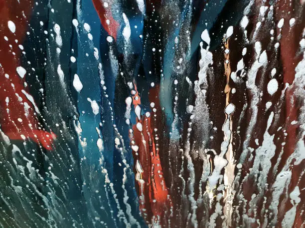 Photo of Car Wash Abstract Soap Sud Bubble Splash Drop Wave Pattern Windshield View from Inside Washing Car Window Blue Red Rags Texture Colorful Grunge Expressionism Background Close-Up