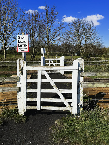 May 8th. 2021. This is the The Evesham Vale light narrow gauge railway at Evesham country park on a sunny day. This is a crossing gate with warning signs. There are no people in the picture.