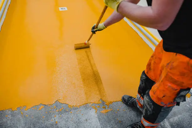Worker applying epoxy and polyurethane flooring system.These easy-to-clean products also have non-slip features.
